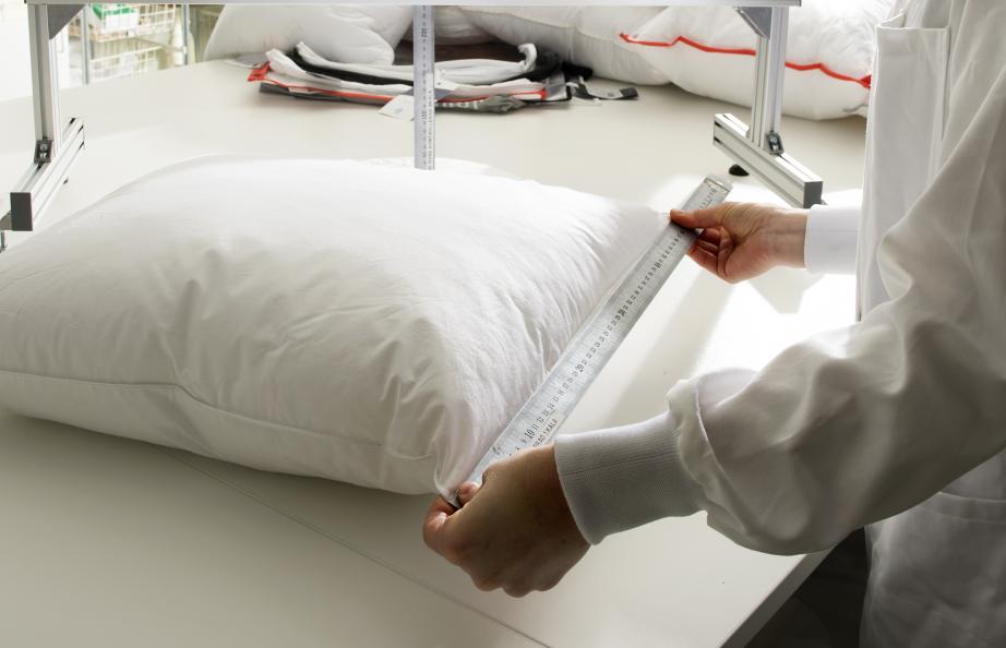 Person mäter längden på kudde med hjälp av linjal.