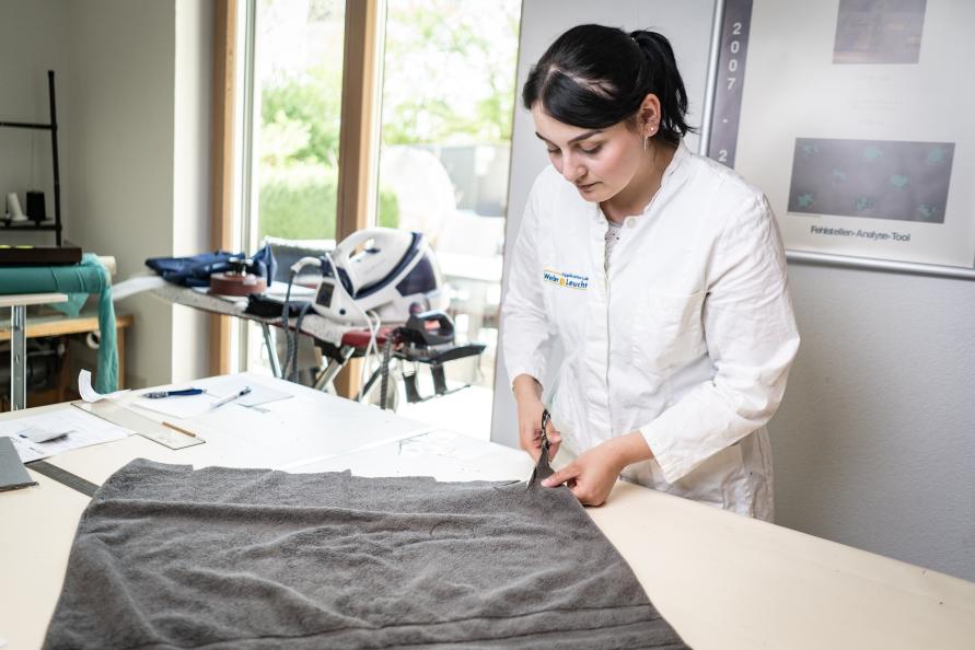 Katarina Röder, statligt certifierad textillaborietekniker, skär ut provkroppar ur handdukarna inför test. Foto: Peter Jülich. 