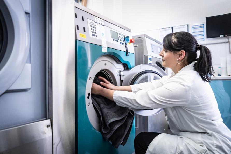 Här lägger Katarina Röder, statligt certifierad textillaboratorietekniker, en handduk i en av labbets tvättmaskiner. Fotograf: Peter Jülich.