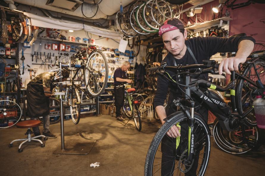 Cykelmekanikern Jovan Lukic justerar bromsarna på en elcykel i verkstaden.